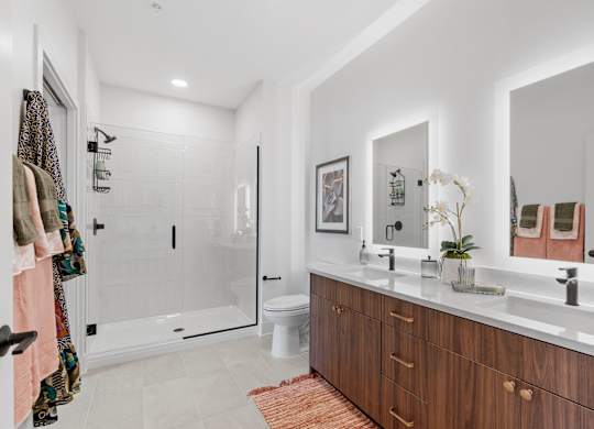 A bathroom with a double-vanity and walk-in shower in a one-bedroom, one-bathroom apartment home at Lilia in Lilydale, MN 55118