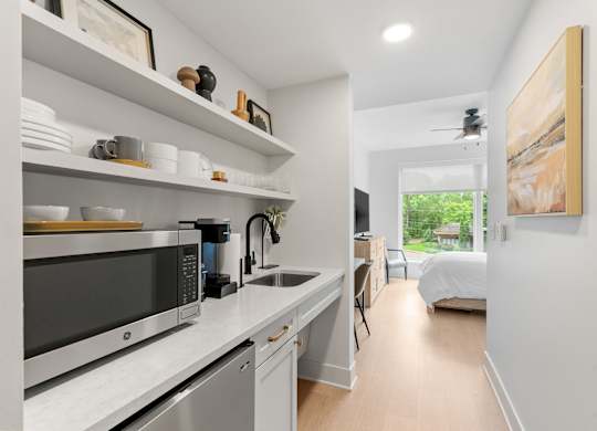 The kitchen featuring a mini fridge, microwave, sink, coffeemaker, toaster, and dishes in the Guest Suite, a reservable community amenity at Lilia in Lilydale, MN 55118