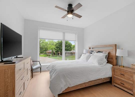 A queen bed, armoire, and TV in the Guest Suite, a reservable community amenity at Lilia in Lilydale, MN 55118