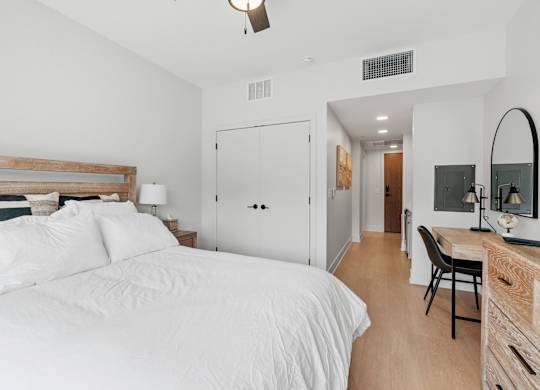 A queen bed, armoire, TV, and kitchenette in the Guest Suite, a reservable community amenity at Lilia in Lilydale, MN 55118. This room also features in-unit laundry and a bathroom.