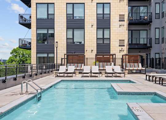 A pool area with lounge chairs and a building in the background.
