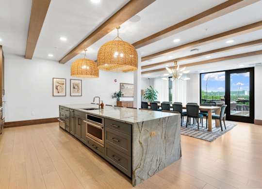 The long dining table and oversized kitchen in the Private Dining Room, a reservable community room at Lilia in Lilydale, MN 55118