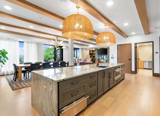 The long dining table and oversized kitchen in the Private Dining Room, a reservable community room at Lilia in Lilydale, MN 55118