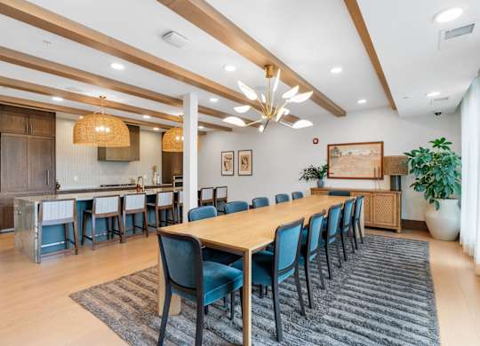 The long dining table and oversized kitchen in the Private Dining Room, a reservable community room at Lilia in Lilydale, MN 55118