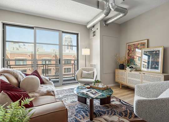 The Ellory - A living room with a brown couch, a grey chair, and a coffee table.