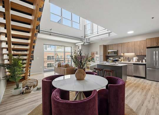 A modern kitchen at The Ellory with a dining table and chairs in the foreground and a staircase on the left.