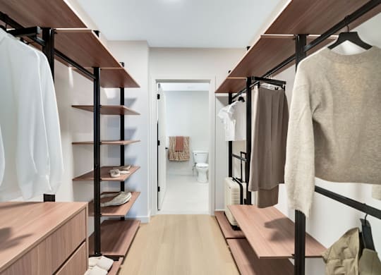 A walk-in closet with clothes hanging and shelves.