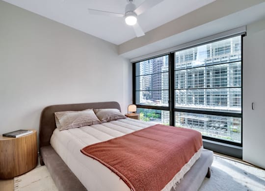 A bedroom with a large bed and a window overlooking a cityscape.  at 17 Market West, Philadelphia, PA