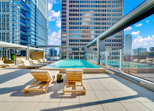 A rooftop pool area with sun loungers and a glass railing overlooking a cityscape. at 17 Market West, Philadelphia Pennsylvania