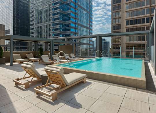 A pool with sun loungers on a balcony overlooking a city. at 17 Market West, Pennsylvania
