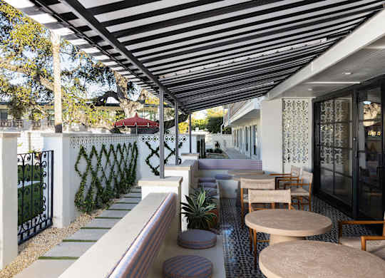 A patio with a black and white striped awning and a table with chairs at The PARKER on E Mulberry Apartments, San Antonio