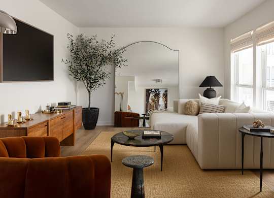 A living room with a white couch, a brown armchair, and a coffee table at The PARKER on E Mulberry Apartments, San Antonio, TX