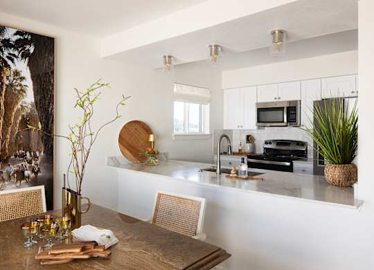 A modern kitchen with a wooden table and chairs at The PARKER on E Mulberry Apartments, Texas