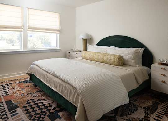 A bedroom with a large bed and a patterned rug at The PARKER on E Mulberry Apartments, Texas