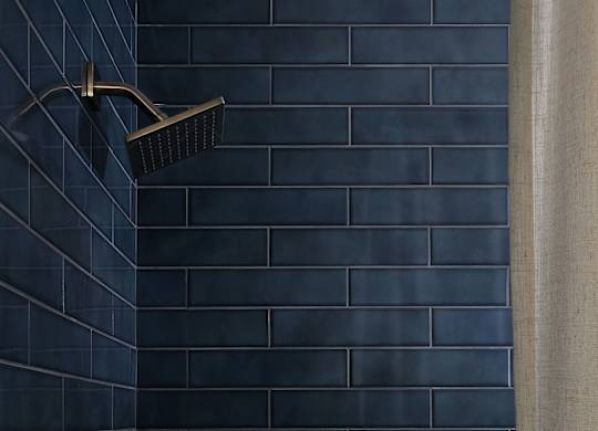 A black shower head mounted on a wall at The PARKER on E Mulberry Apartments, Texas
