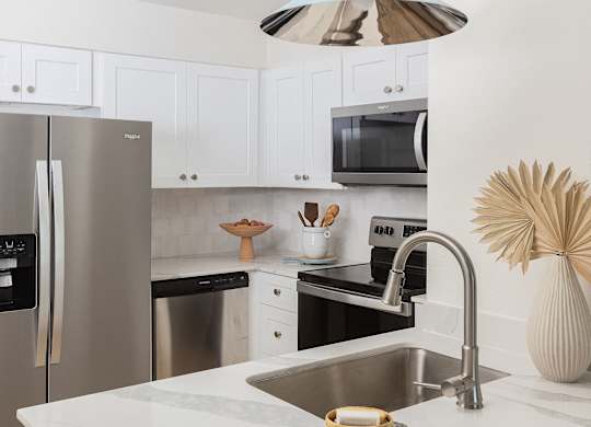 A modern kitchen with a stainless steel refrigerator and a white countertop at The PARKER on E Mulberry Apartments, San Antonio, Texas