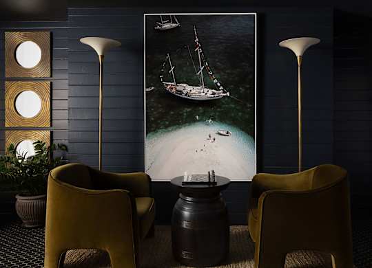 A room with a large picture of a boat on the wall and two yellow chairs at The PARKER on E Mulberry Apartments, San Antonio, Texas