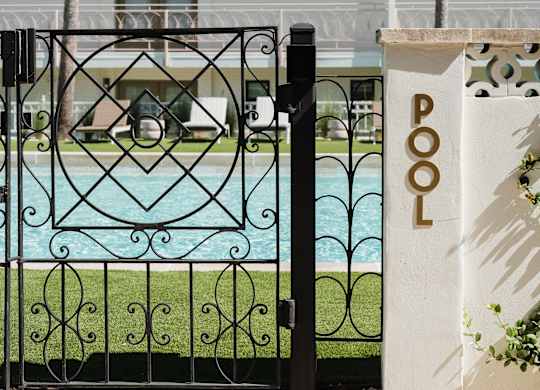 A pool with a black fence and a white pillar with the word POOL on it at The PARKER on E Mulberry Apartments, San Antonio, TX