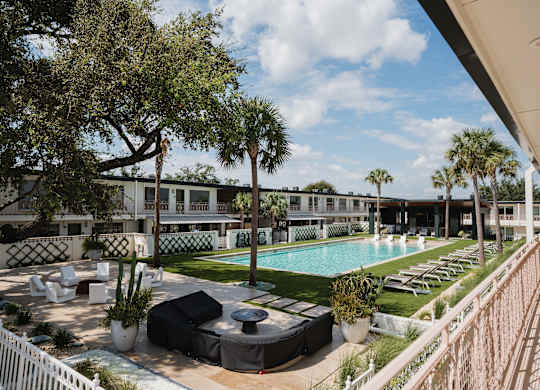 A pool area with lounge chairs and a white fence at The PARKER on E Mulberry Apartments, San Antonio, TX, 78209