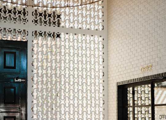 A white patterned screen separates the lobby from the office area at The PARKER on E Mulberry Apartments, San Antonio, 78209