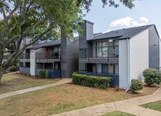 a grey and blue apartment building with balconies and a sidewalk at District 2308, Arlington, 76011 
