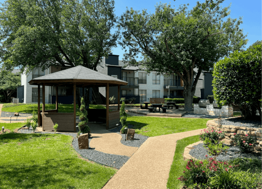 a park with a gazebo and trees in front of an apartment building at District 2308, Texas 