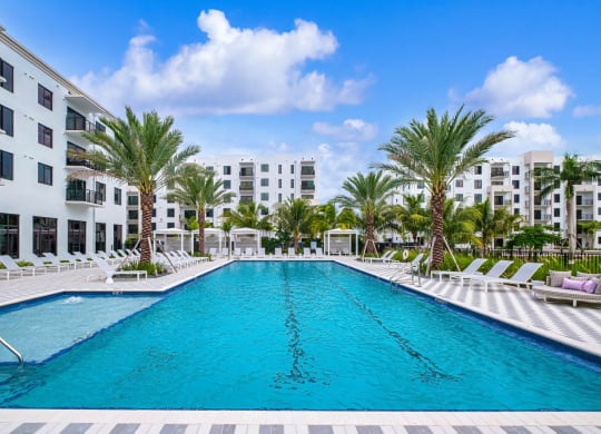 a swimming pool with palm trees in front of an apartment building at Altis Grand Kendall, Miami, FL 33186