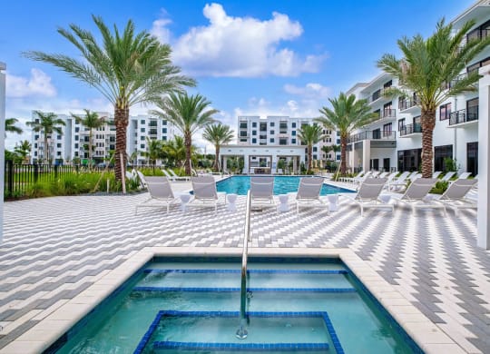 a swimming pool with white chairs and a blue fountain at Altis Grand Kendall, Miami