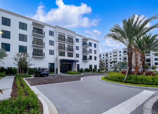 an exterior view of an apartment building with a driveway and palm trees at Altis Grand Kendall, Miami, FL 33186