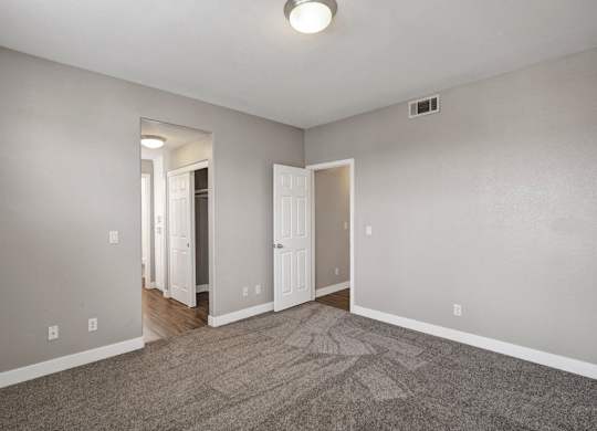 A room with a carpeted floor and a doorway leading to another room.