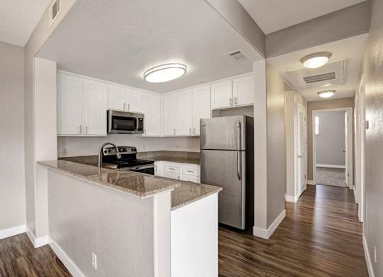 A kitchen with a refrigerator, microwave, and oven.