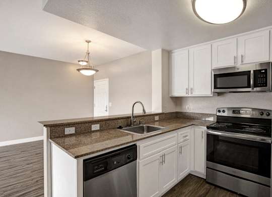 A kitchen with white cabinets and a granite countertop.