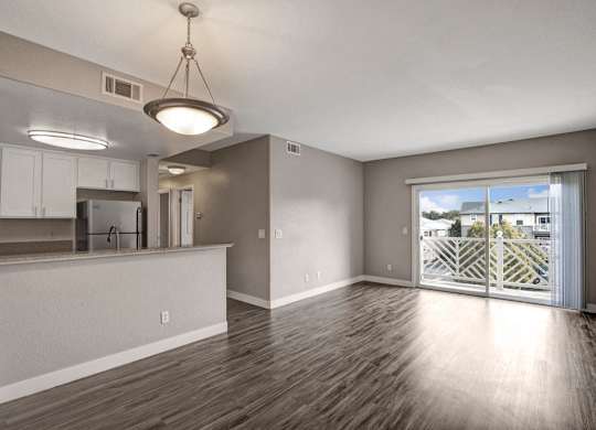 A well-lit, spacious room with wooden flooring and a large window.