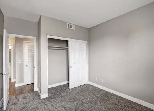 A room with a white door and a carpeted floor.