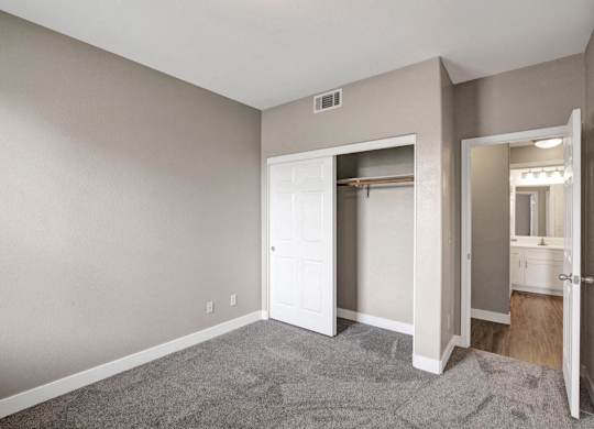 A room with a white door and a grey carpet.