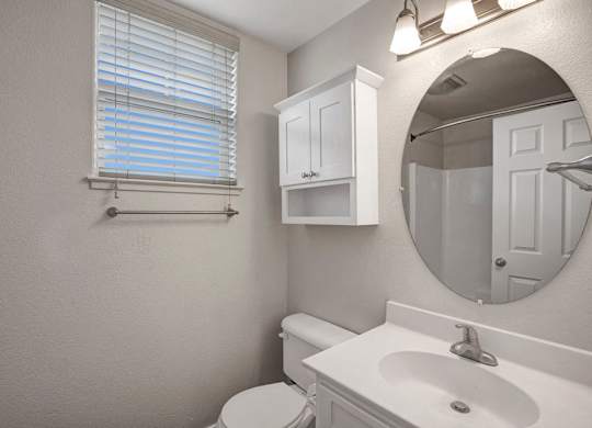 A bathroom with a toilet, sink, and mirror.