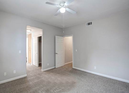 A room with a ceiling fan and carpeted floor.