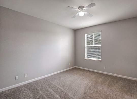 A room with a ceiling fan and a window with blinds.
