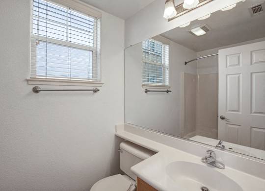 A white bathroom with a toilet, sink, and mirror.
