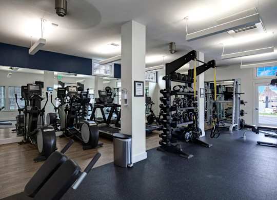 A gym with a variety of equipment including treadmills, weights, and exercise machines.