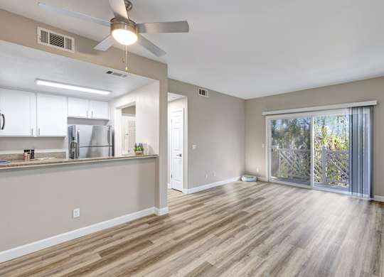 A room with a ceiling fan and sliding glass doors.
