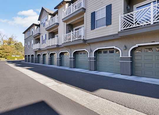 A row of garages in front of a building with balconies.
