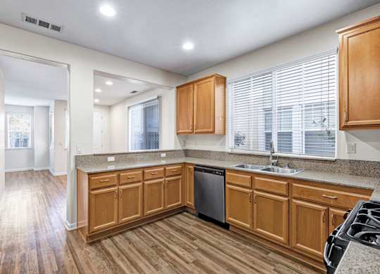 A kitchen with wooden cabinets and a black dishwasher.
