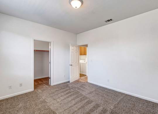 A room with a carpeted floor and two doors.