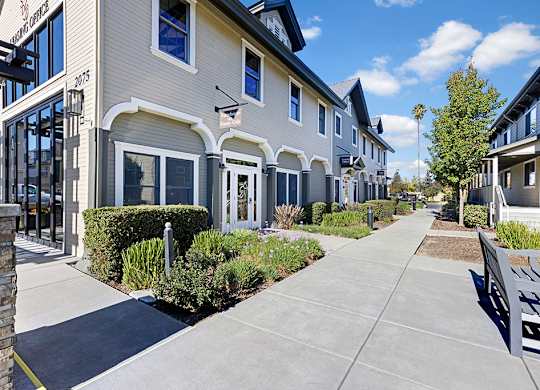 A row of houses with a sidewalk in front.