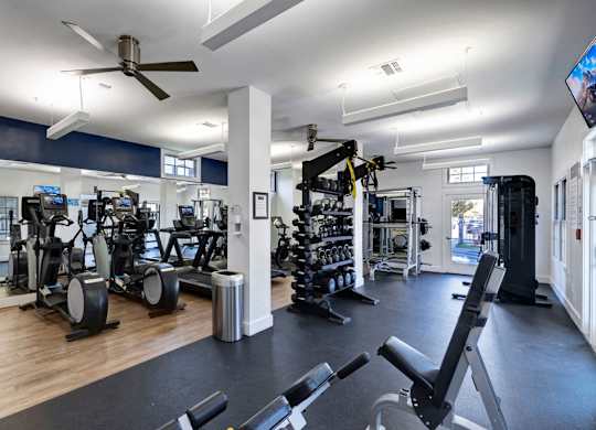 A gym with a variety of equipment including treadmills, weights, and exercise machines.
