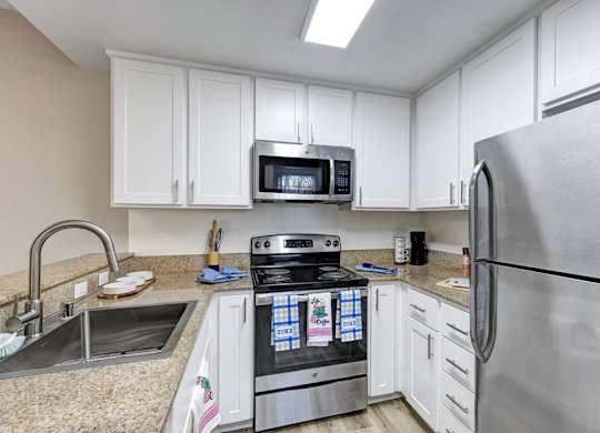 A kitchen with a stove, microwave, and refrigerator.