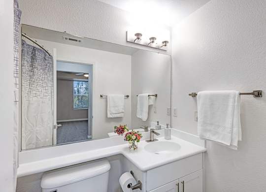 A white bathroom with a toilet, sink, and mirror.
