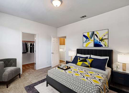 A bedroom with a large bed and a chair.