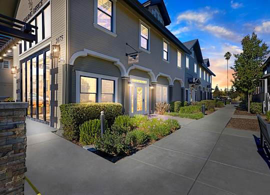A row of houses with a sidewalk in front.